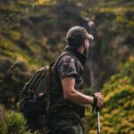 HOME Man with hiking gear explores lush forest landscape, embodying adventure and nature.